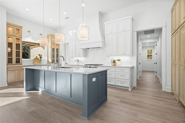 kitchen featuring light hardwood / wood-style floors, white cabinetry, sink, and a large island with sink