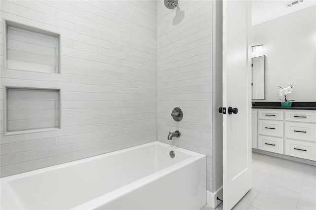 bathroom featuring tile patterned flooring, vanity, and tiled shower / bath