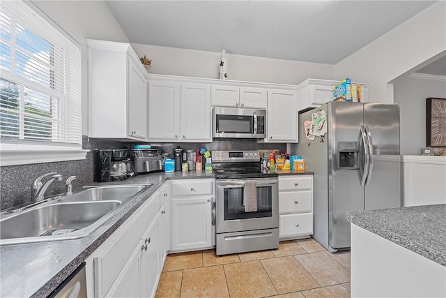 kitchen featuring decorative backsplash, stainless steel appliances, sink, light tile patterned floors, and white cabinets