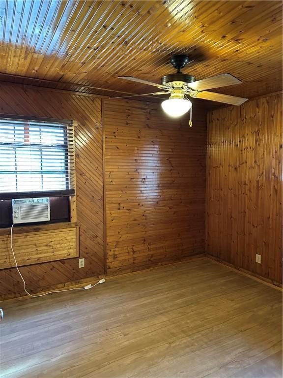 unfurnished room with wooden walls and wood-type flooring