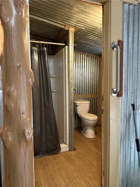 bathroom with hardwood / wood-style flooring, toilet, and walk in shower