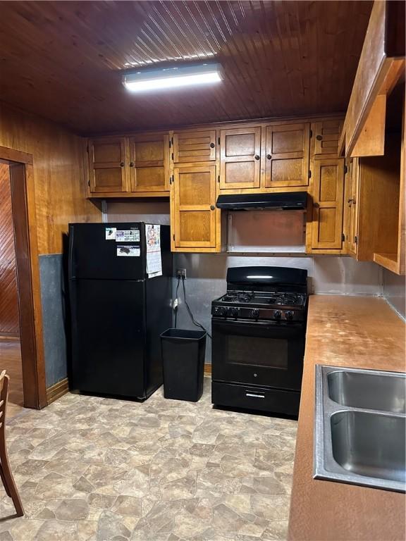 kitchen with wooden walls, sink, black appliances, and wooden ceiling