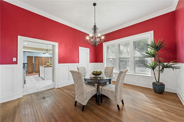 dining space with light hardwood / wood-style floors, crown molding, and an inviting chandelier