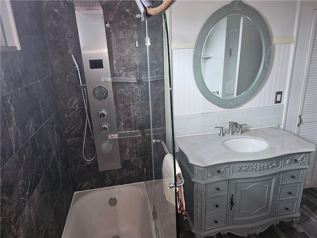 bathroom with hardwood / wood-style flooring, vanity, and tiled shower / bath