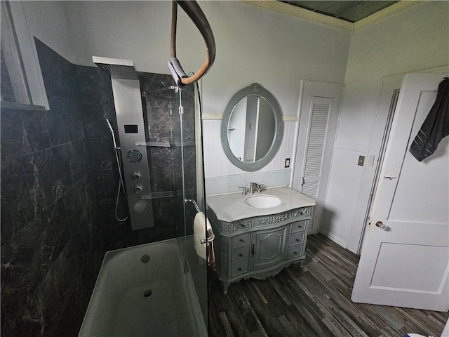 bathroom with vanity, crown molding, wood-type flooring, and tiled shower / bath