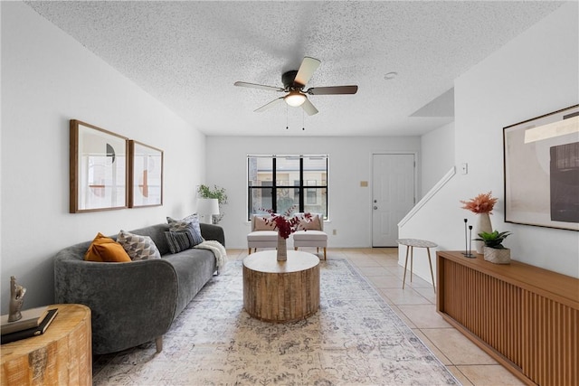 living area featuring a textured ceiling, light tile patterned flooring, and a ceiling fan