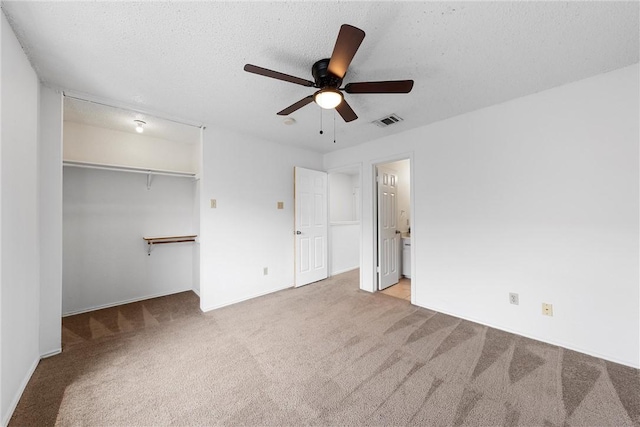 unfurnished bedroom featuring carpet flooring, a textured ceiling, ensuite bathroom, and visible vents