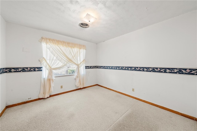 carpeted empty room with baseboards, visible vents, and a textured ceiling