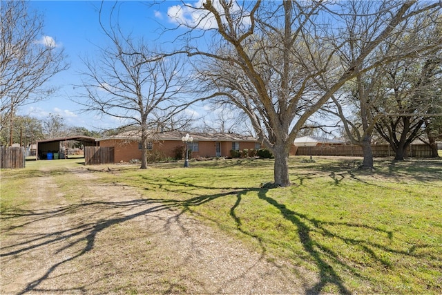 view of yard featuring a carport, driveway, and fence