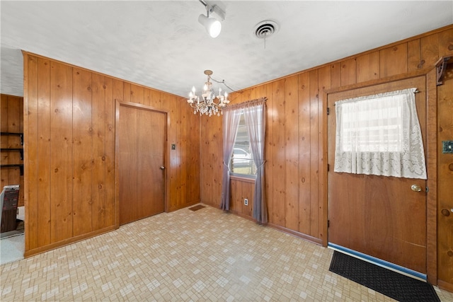 interior space with visible vents, wooden walls, baseboards, tile patterned floors, and a notable chandelier