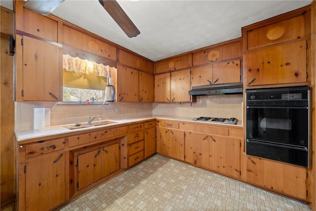 kitchen with a warming drawer, tasteful backsplash, under cabinet range hood, and stainless steel gas cooktop