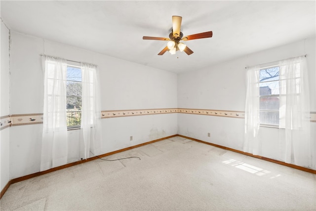 carpeted spare room featuring a healthy amount of sunlight, baseboards, and ceiling fan