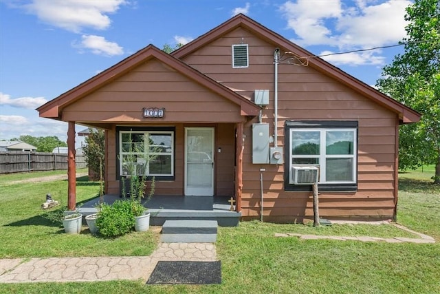 bungalow-style house with cooling unit and a front lawn