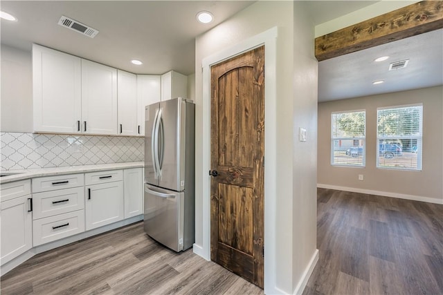 kitchen with decorative backsplash, white cabinetry, stainless steel fridge, and light hardwood / wood-style flooring