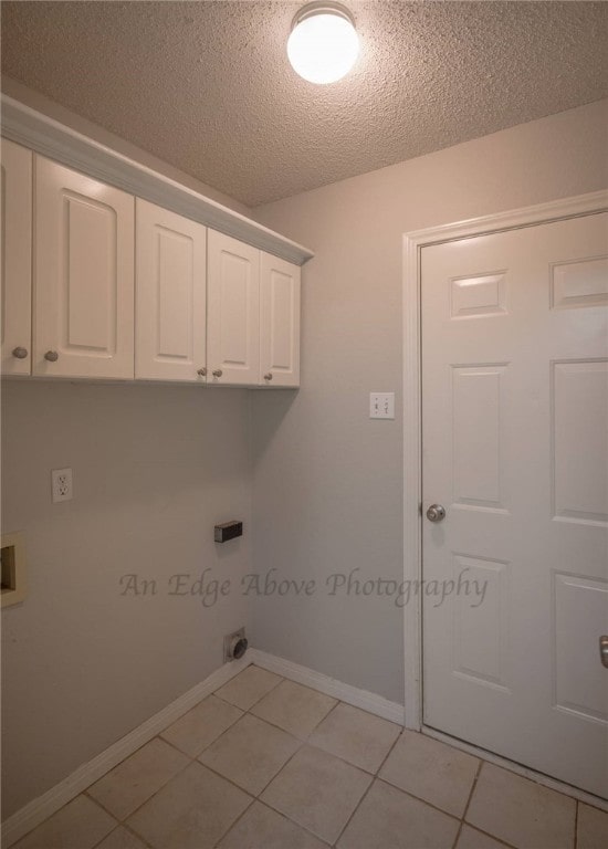 laundry area with a textured ceiling, light tile patterned floors, hookup for a washing machine, electric dryer hookup, and cabinets