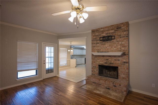 unfurnished living room featuring crown molding, hardwood / wood-style flooring, a textured ceiling, and a brick fireplace