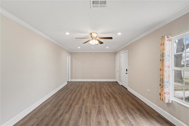 empty room with visible vents, crown molding, baseboards, and wood finished floors