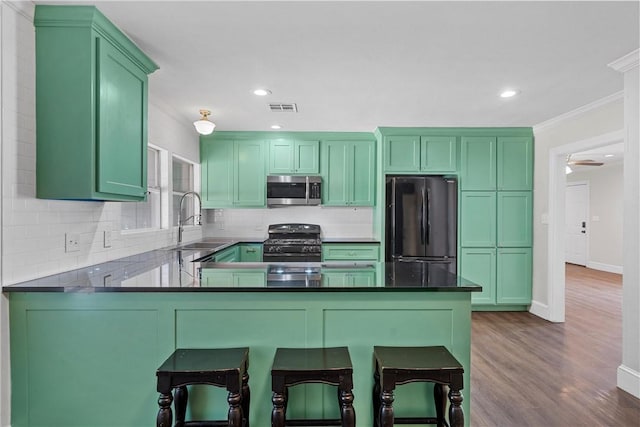 kitchen featuring visible vents, freestanding refrigerator, stainless steel microwave, range with gas cooktop, and green cabinetry