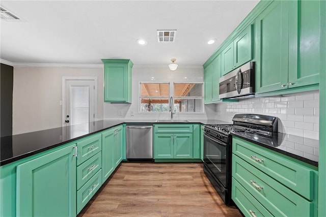 kitchen featuring appliances with stainless steel finishes, dark countertops, visible vents, and a sink