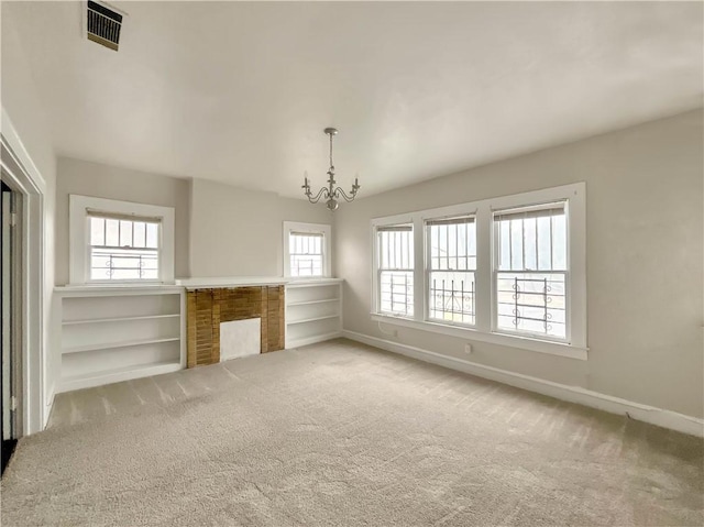 unfurnished living room featuring carpet flooring, a wealth of natural light, and a notable chandelier