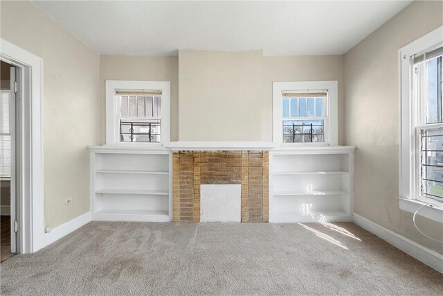 unfurnished living room featuring a fireplace, plenty of natural light, carpet, and a notable chandelier