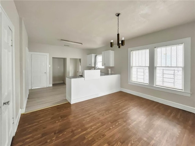 unfurnished living room featuring a chandelier, dark hardwood / wood-style floors, and sink