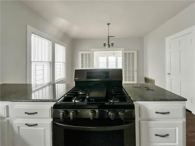 kitchen featuring hanging light fixtures, black gas stove, white cabinetry, and a wealth of natural light