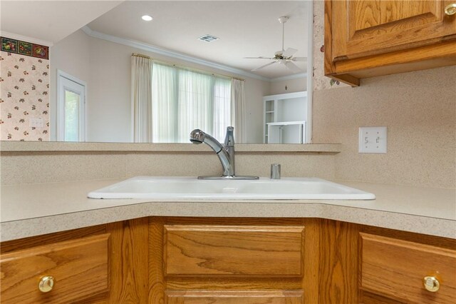 kitchen with ornamental molding, ceiling fan, a healthy amount of sunlight, and sink