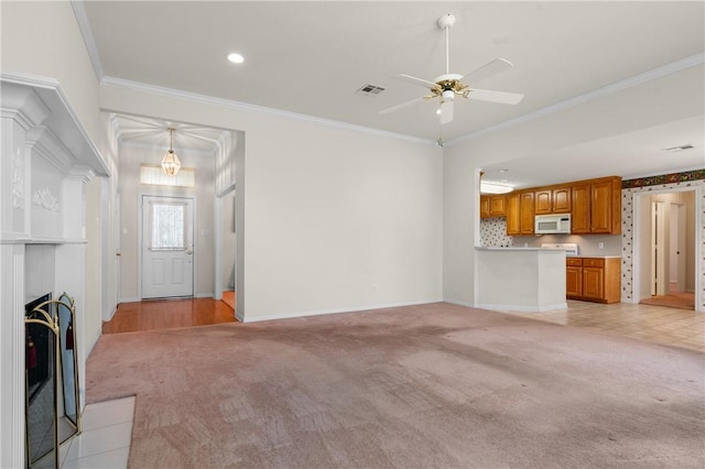 unfurnished living room featuring light colored carpet, ceiling fan, and crown molding