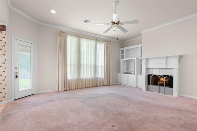 unfurnished living room with a tiled fireplace, crown molding, ceiling fan, and light colored carpet