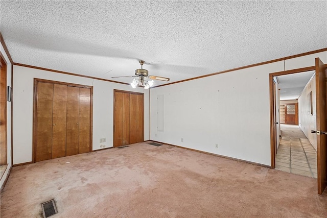 unfurnished bedroom featuring ceiling fan, ornamental molding, a textured ceiling, and light carpet