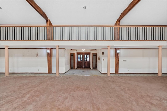 unfurnished living room featuring beam ceiling, a towering ceiling, light carpet, and decorative columns