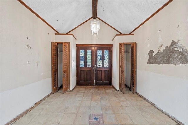 entrance foyer with a chandelier, ornamental molding, a textured ceiling, and french doors