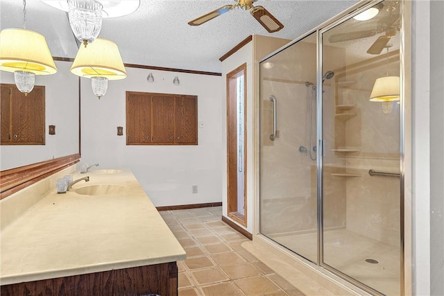 bathroom with a shower with door, vanity, a textured ceiling, and ornamental molding