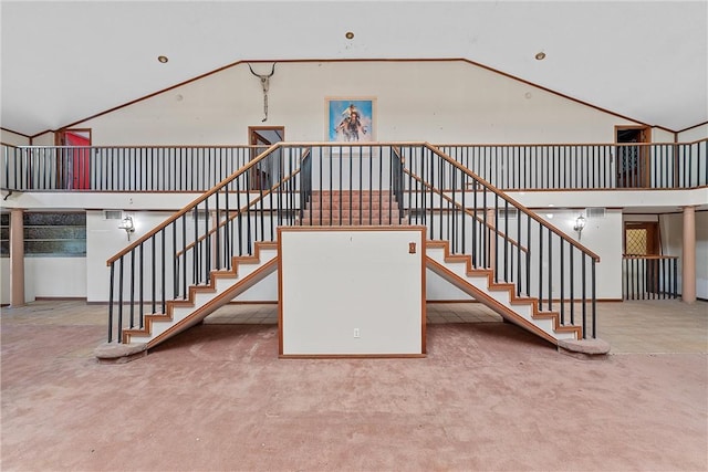 stairway with carpet and high vaulted ceiling