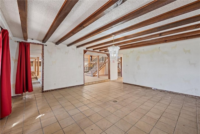 tiled spare room featuring beamed ceiling, a textured ceiling, and a notable chandelier