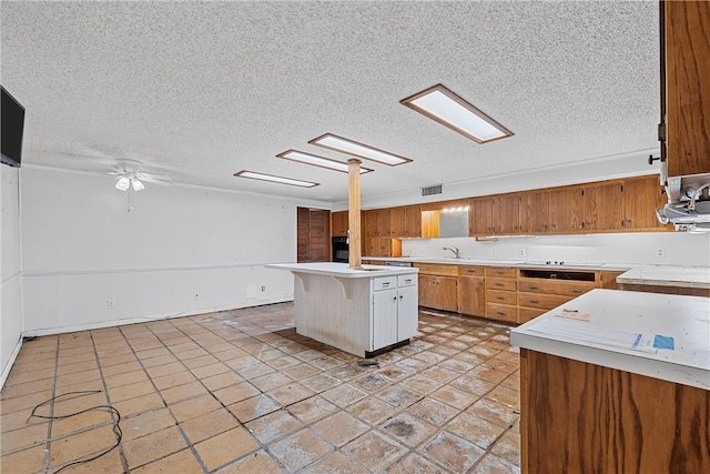 kitchen featuring a breakfast bar, a textured ceiling, a kitchen island, ceiling fan, and black oven