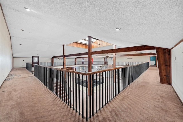 hallway featuring a textured ceiling, carpet floors, and lofted ceiling