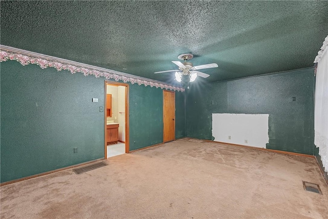 unfurnished bedroom with a textured ceiling, carpet floors, ensuite bath, and ceiling fan