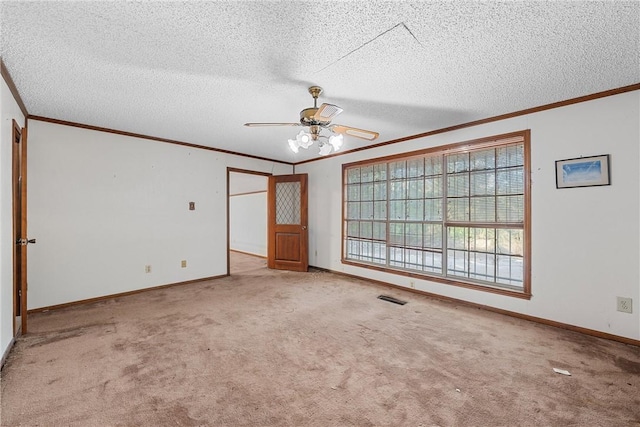 empty room featuring a textured ceiling, light colored carpet, ceiling fan, and crown molding