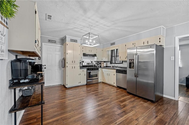 kitchen with cream cabinetry, a textured ceiling, dark hardwood / wood-style flooring, and stainless steel appliances