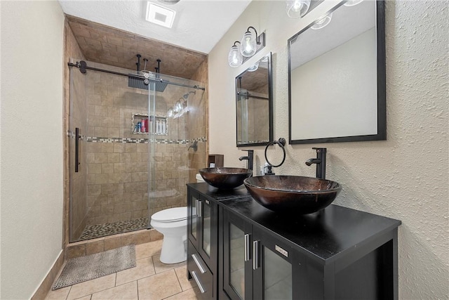 bathroom featuring tile patterned flooring, vanity, toilet, and walk in shower