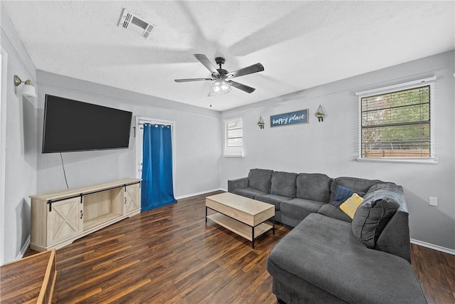 living room featuring ceiling fan, dark hardwood / wood-style flooring, and a textured ceiling