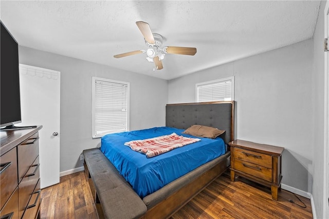 bedroom with ceiling fan, dark wood-type flooring, and a textured ceiling