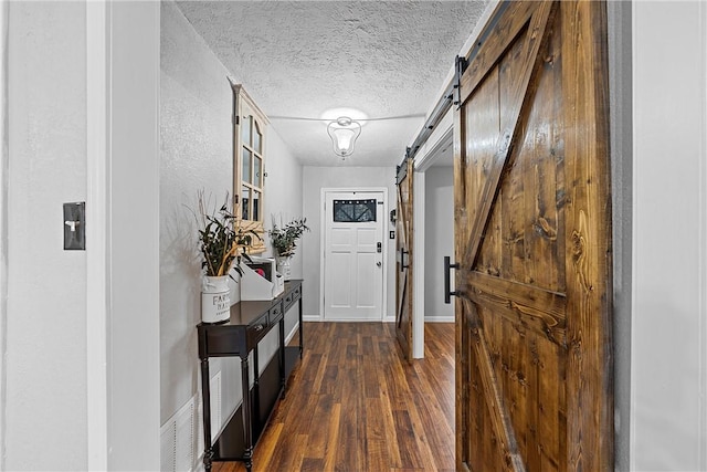 entryway featuring a barn door, dark hardwood / wood-style flooring, and a textured ceiling