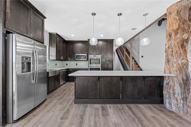 kitchen featuring decorative light fixtures, dark brown cabinets, stainless steel appliances, and light hardwood / wood-style flooring