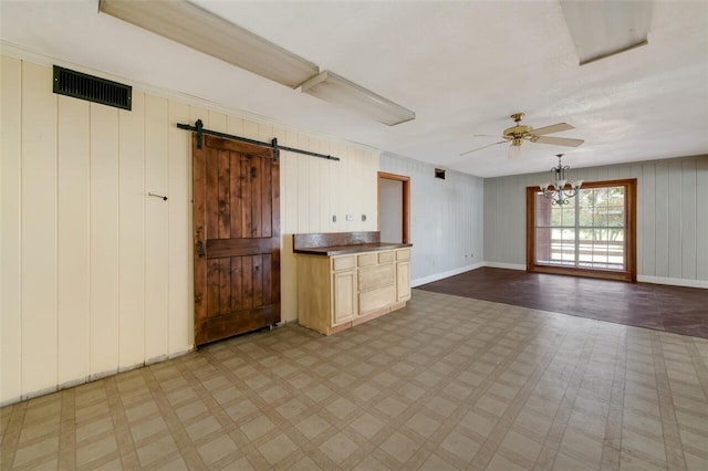 kitchen with pendant lighting, ceiling fan with notable chandelier, a barn door, light brown cabinetry, and light hardwood / wood-style floors