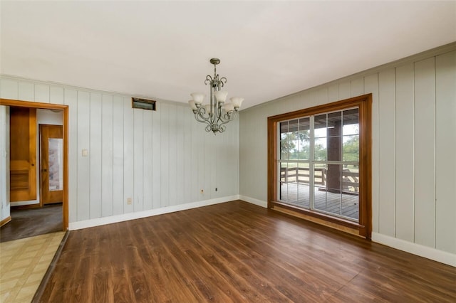 empty room with a chandelier and dark hardwood / wood-style floors