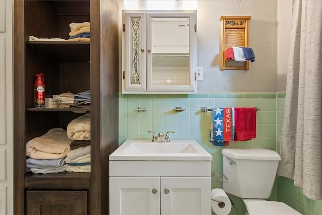 bathroom with vanity, toilet, and tile walls