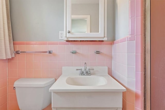 bathroom featuring vanity, toilet, and tile walls